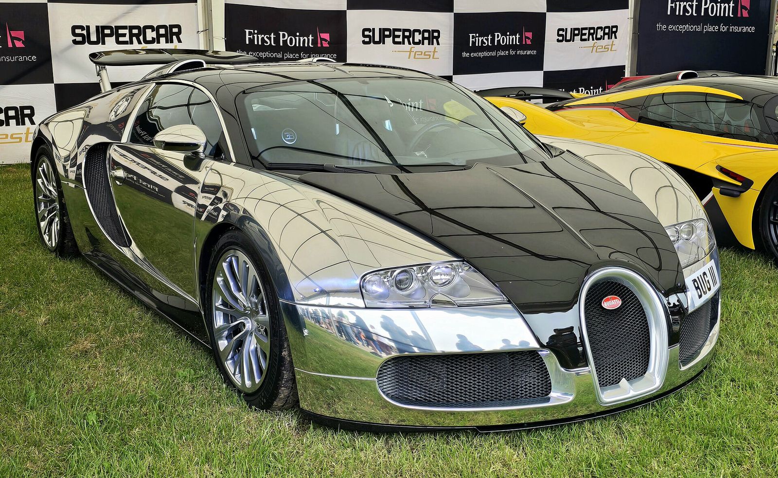 Bugatti Veyron with a polished chrome and black body, displayed on grass at a supercar event