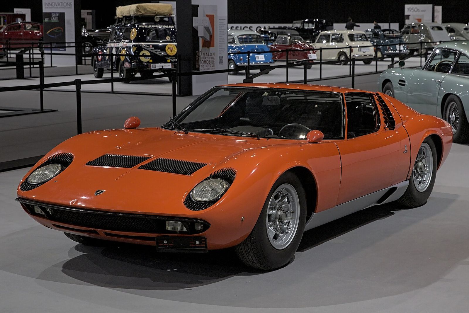 Orange Lamborghini Miura P400 S on display at an indoor motor show