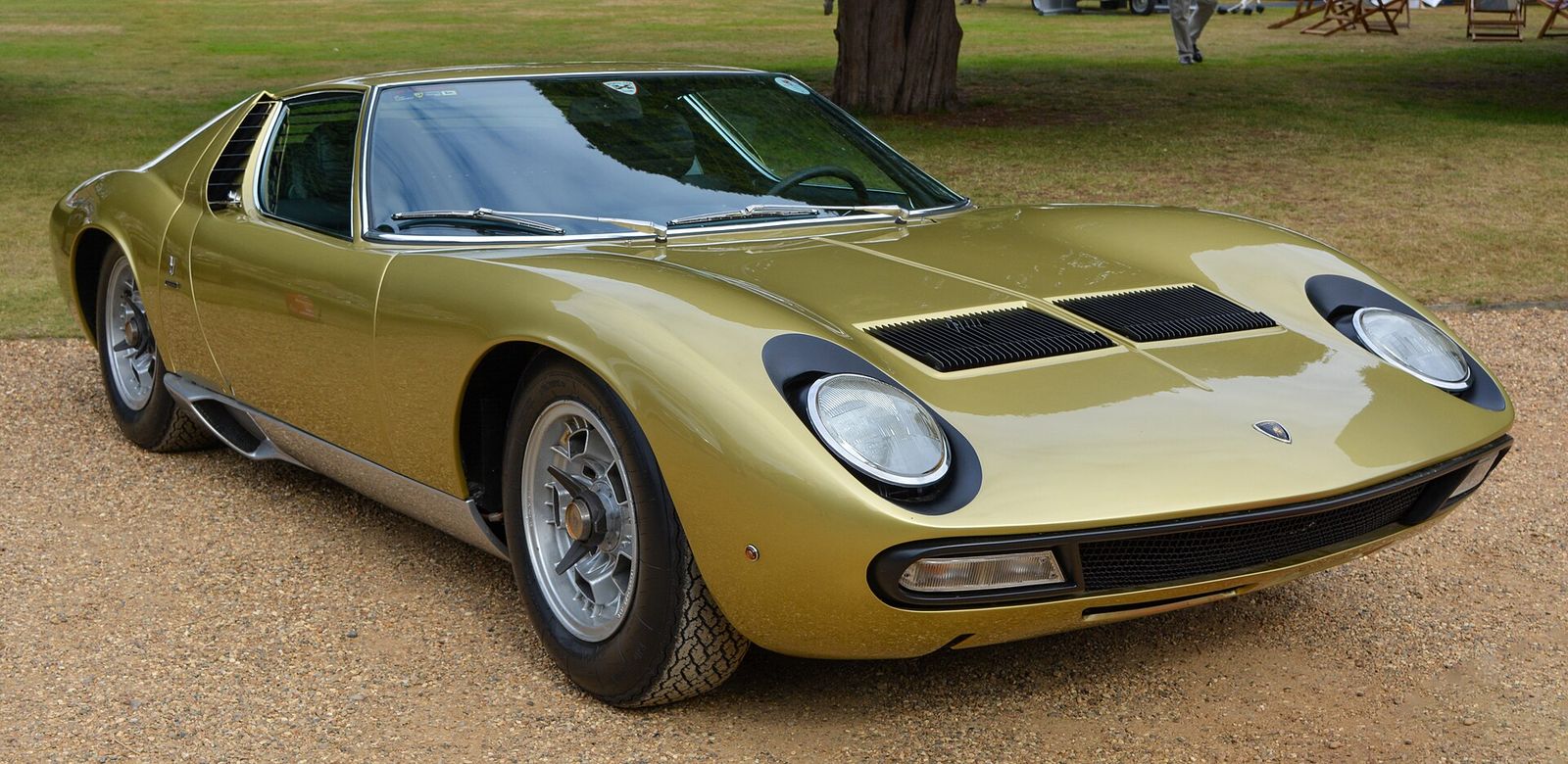 Gold 1971 Lamborghini Miura P400 SV parked on gravel at a concours event