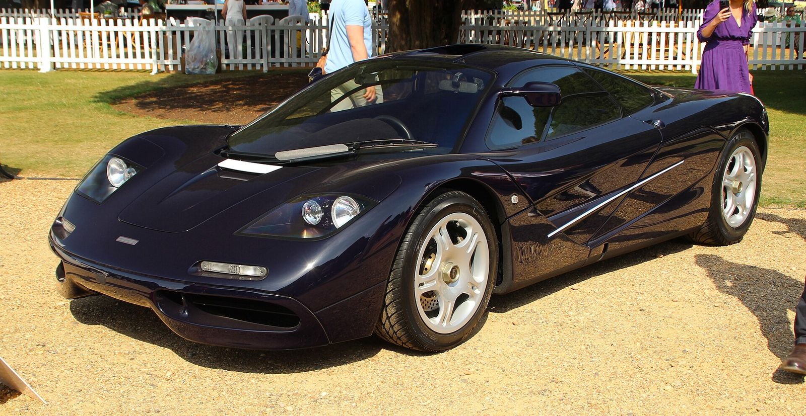 Dark blue 1995 McLaren F1 parked on gravel at a concours event